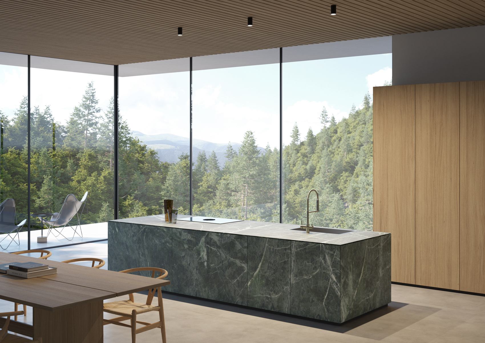 Cucina con isola in marmo verde e grande vetrata sul bosco