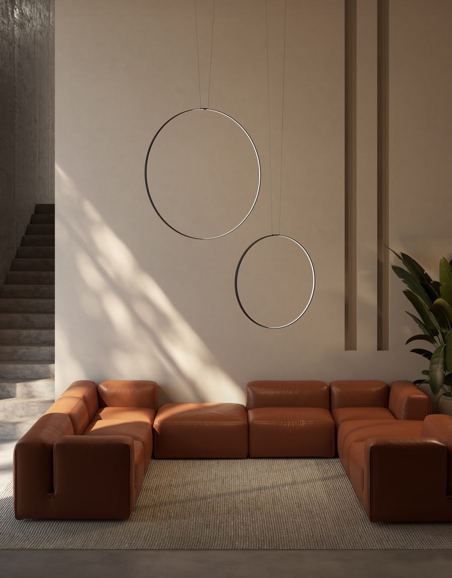 Salotto con divano in pelle color terracotta e due lampade ad anello
