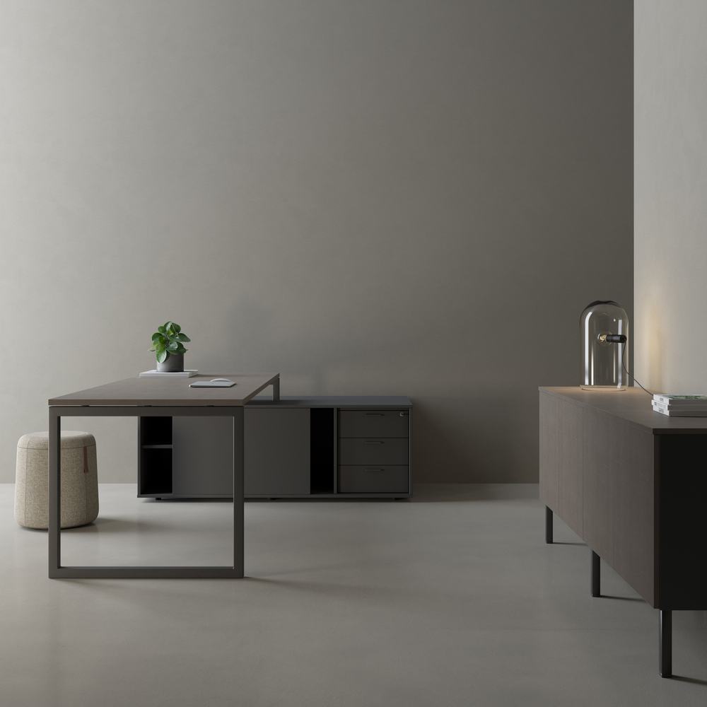 Scrivania grigia con pouf e credenza scura in un ambiente minimale