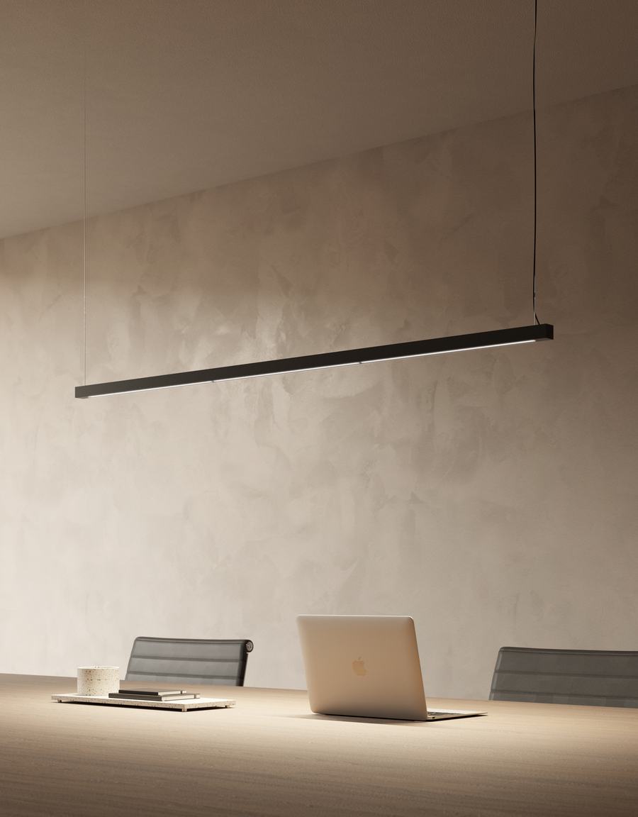 Lampada lineare sospesa sopra un tavolo con computer portatile