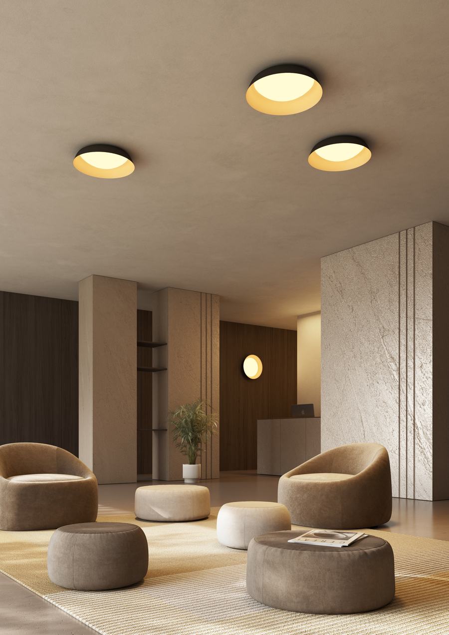 Zona lounge con pouf e poltroncine tonde color tortora e plafoniere circolari