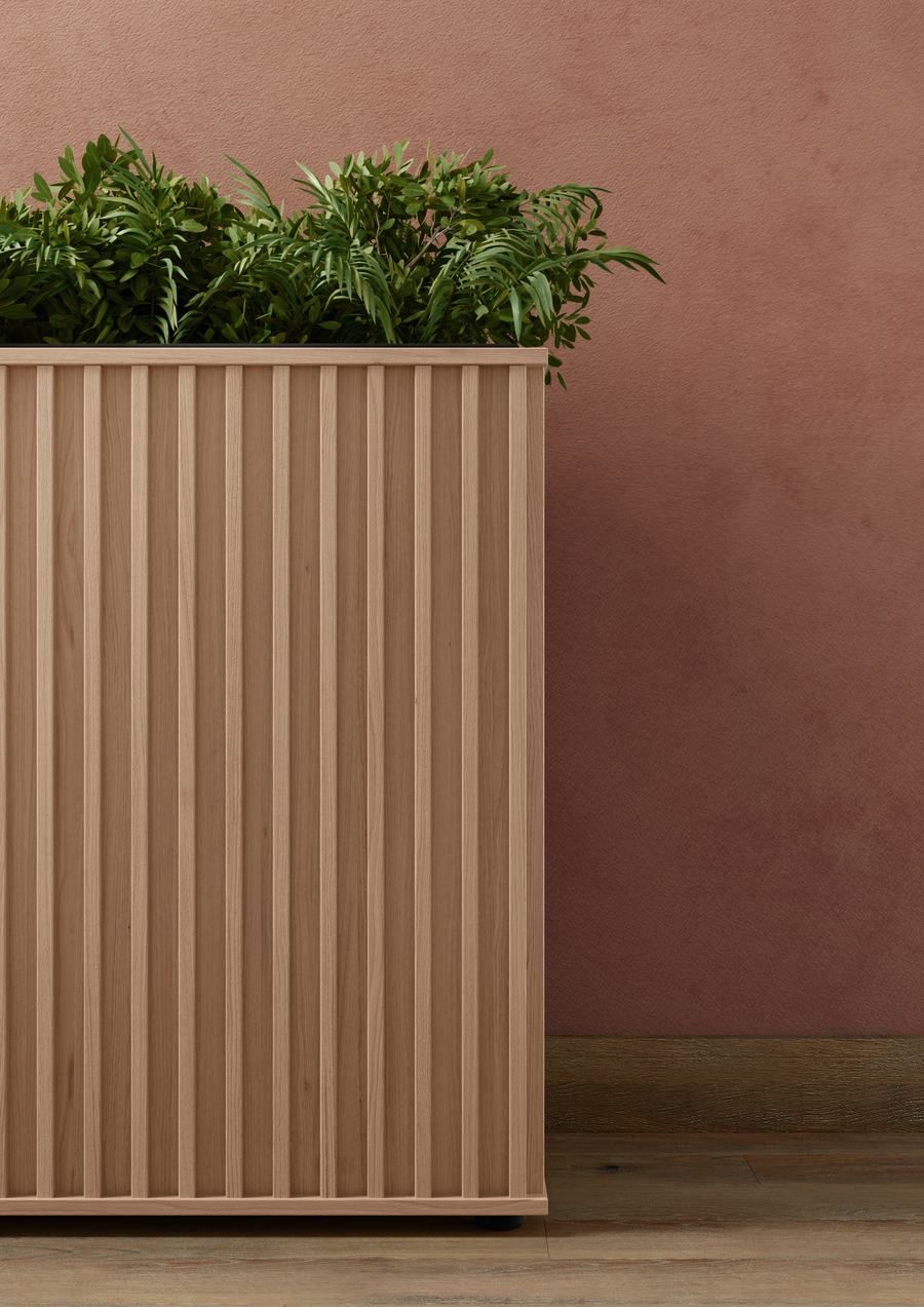 Fioriera in legno scanalato con piante su una parete color terracotta